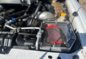 A red air filter is sitting under the hood of a car